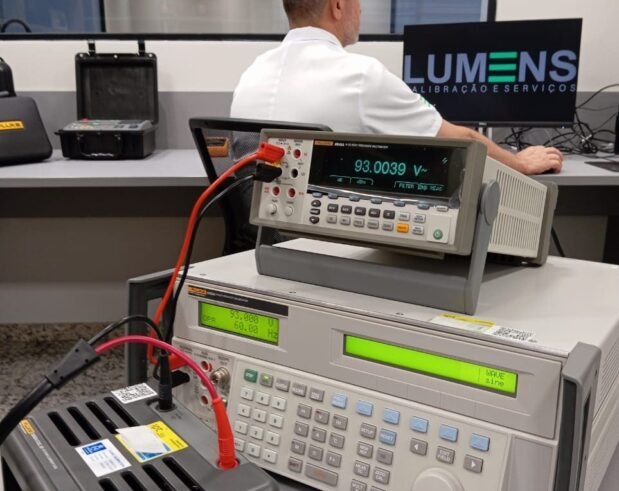 A calibração de instrumentos de medição é fundamental para um bom controle de processo de produção e diagnóstico em uma empresa. Descrição da imagem: Um multímetro digital de referência, usado na calibração de instrumentos de medição, o multímetro encontra-se sobre uma bancada de cor cinza em um laboratório de calibração. A Lumens Calibração situado em Guarulhos, São Paulo. Realizamos atendimento em todo Brasil. Um técnico da Empresa Lumens Calibração realizando a calibração de um instrumento de medição chamado alicate amperímetro, na bancada de calibração há um computador preto com o logo da empresa Lumens, ao lado esquerdo há um padrão de teste e uma bobina geradora de corrente para calibração do sensor de corrente do alicate amperímetro. A Lumens Calibração situado em Guarulhos, São Paulo. Realizamos atendimento em todo Brasil.