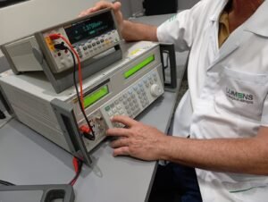 A calibração de instrumentos de medição é fundamental para um bom controle de processo de produção e diagnóstico. Descrição da imagem: Um técnico da Empresa Lumens Calibração realizando a calibração de um instrumento de medição chamado alicate amperímetro, na bancada de calibração há um computador preto com o logo da empresa Lumens, ao lado esquerdo há um padrão de teste e uma bobina geradora de corrente para calibração do sensor de corrente do alicate amperímetro. A Lumens Calibração situado em Guarulhos, São Paulo. Realizamos atendimento em todo Brasil.